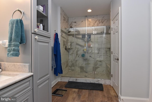 bathroom featuring a stall shower, recessed lighting, wood finished floors, vanity, and baseboards