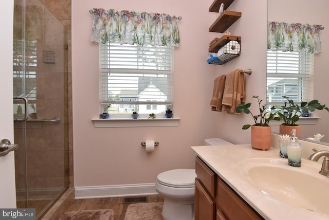 full bath featuring a stall shower, vanity, toilet, and baseboards