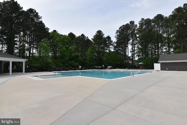 community pool with a patio and view of scattered trees