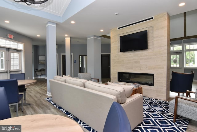 living area with a fireplace, plenty of natural light, ornate columns, recessed lighting, and wood finished floors