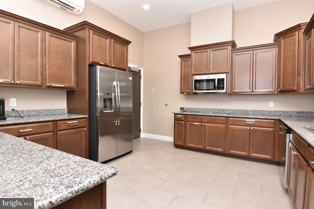 kitchen with appliances with stainless steel finishes, baseboards, light stone counters, an AC wall unit, and recessed lighting