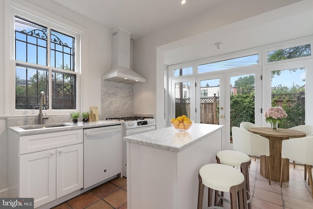 108 3rd St NE, Washington, DC 20002 - kitchen featuring wall chimney range hood, white dishwasher, a center island, decorative backsplash, and white cabinets