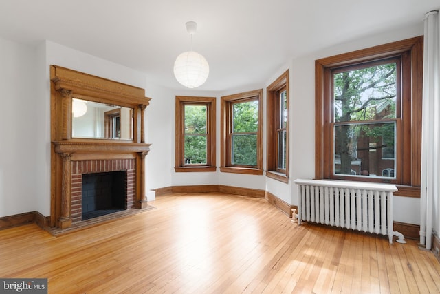 108 3rd St NE, Washington, DC 20002 - unfurnished living room featuring radiator, light wood-style flooring, and a brick fireplace