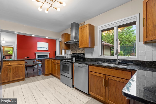 kitchen with a sink, wall chimney range hood, stainless steel appliances, and brown cabinets