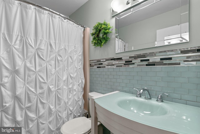bathroom with a sink, toilet, backsplash, tile walls, and a shower with curtain