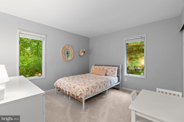 bedroom with light colored carpet and baseboards