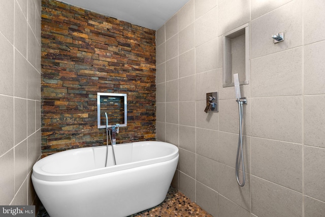full bathroom featuring tile walls and a freestanding bath