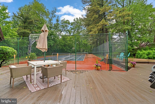 view of tennis court with fence and a deck