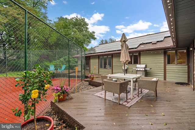 deck with outdoor dining space, fence, and area for grilling