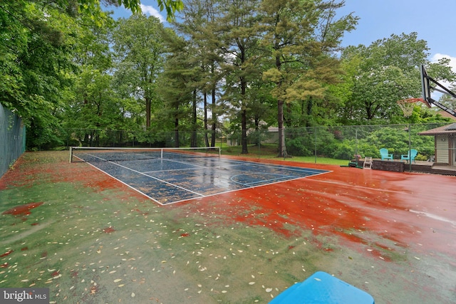 view of tennis court with fence and view of wooded area
