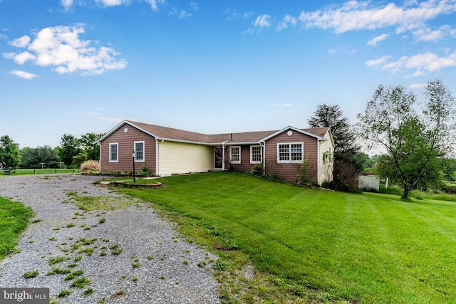 ranch-style house featuring driveway and a front lawn