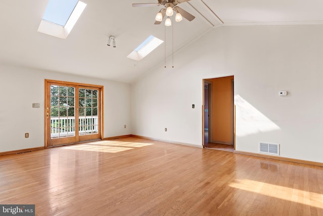 empty room featuring a skylight, ceiling fan, high vaulted ceiling, baseboards, and light wood-style flooring