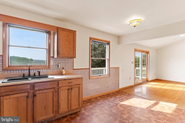kitchen with a sink, brown cabinets, light countertops, tile patterned floors, and baseboards