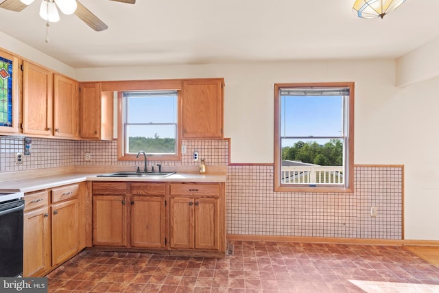 kitchen featuring a sink, light countertops, ceiling fan, electric range, and a wainscoted wall