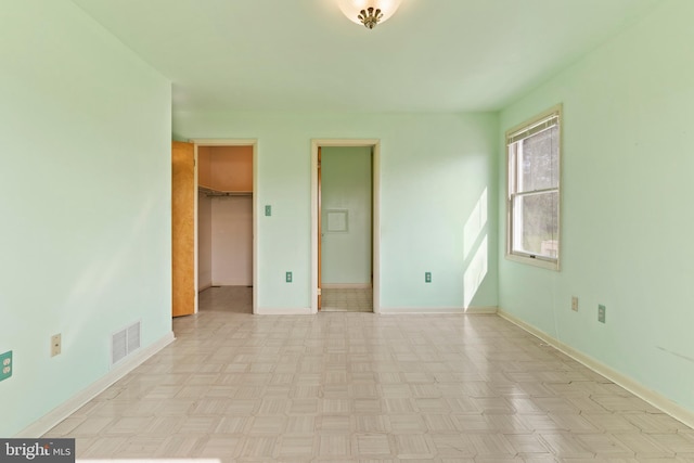 unfurnished bedroom with baseboards and a spacious closet