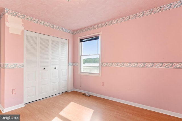 unfurnished bedroom with wood finished floors, a closet, and baseboards