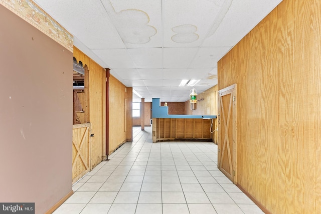 hall with wooden walls and light tile patterned floors