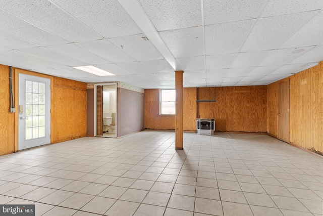 basement featuring wood walls and a paneled ceiling