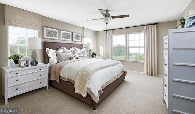 carpeted bedroom featuring multiple windows, baseboards, and ceiling fan
