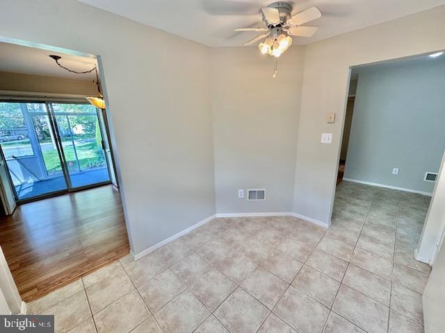 empty room with ceiling fan, light tile patterned floors, and baseboards