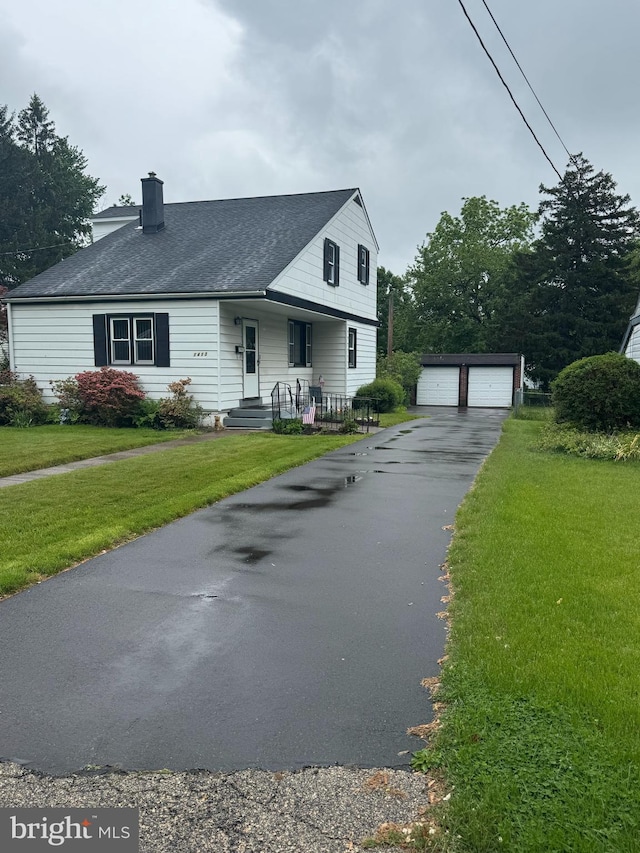 view of front of house featuring an outdoor structure, a chimney, a detached garage, and a front lawn