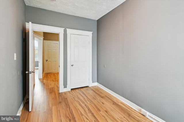 1081 Ellicott Dr, Baltimore, MD 21216 - unfurnished bedroom with baseboards, light wood-style flooring, and a textured ceiling