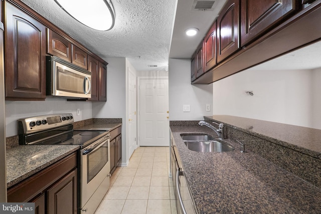 13113 Briarcliff Ter Unit 1-101, Germantown, MD 20874 - kitchen with stainless steel appliances, a sink, light tile patterned floors, a textured ceiling, and dark stone counters
