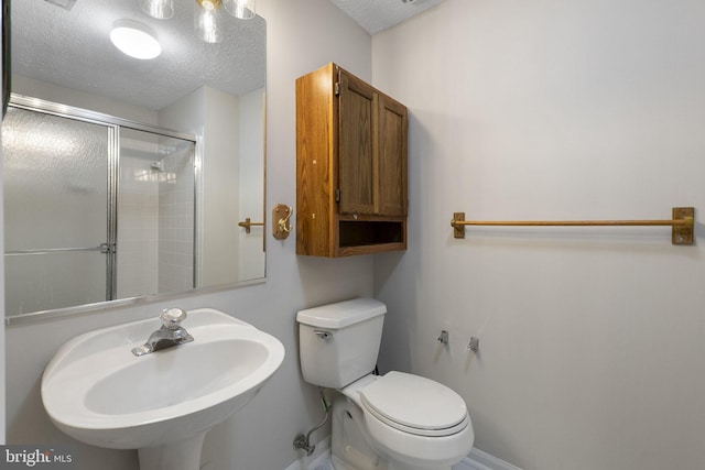 13113 Briarcliff Ter Unit 1-101, Germantown, MD 20874 - bathroom featuring a sink, a textured ceiling, toilet, a shower with shower door, and baseboards