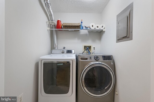 13113 Briarcliff Ter Unit 1-101, Germantown, MD 20874 - laundry area with electric panel, washing machine and clothes dryer, and a textured ceiling