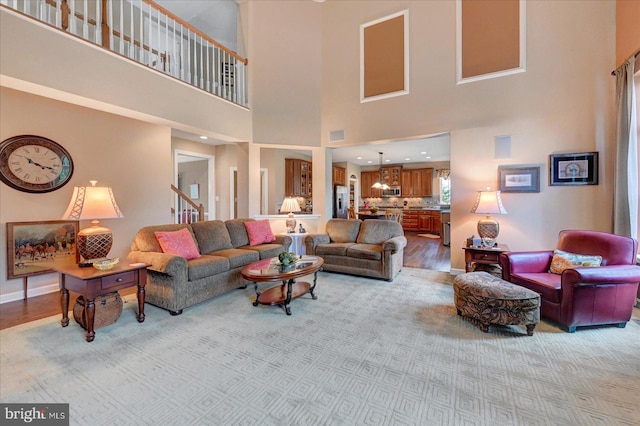 living area featuring light wood-type flooring and a high ceiling