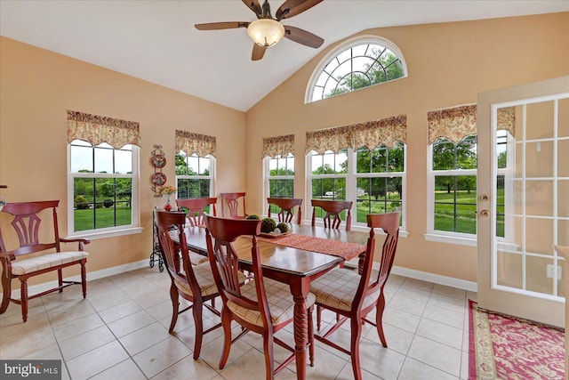 dining space with light tile patterned floors, ceiling fan, baseboards, and high vaulted ceiling