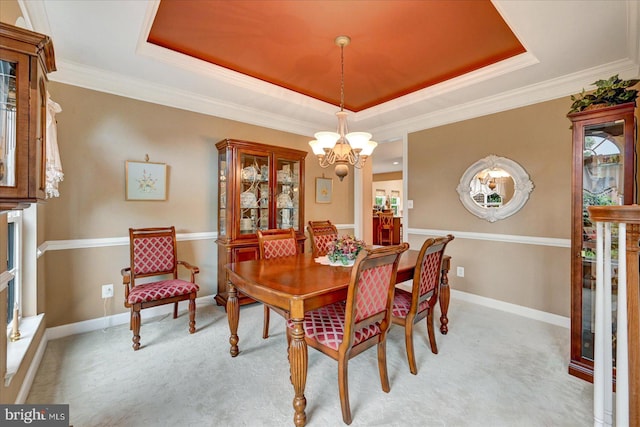 dining room with a raised ceiling, a chandelier, light colored carpet, and crown molding
