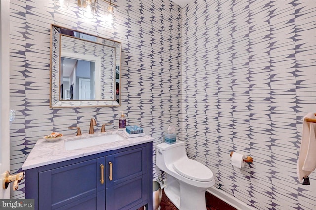 bathroom with wallpapered walls, toilet, and vanity