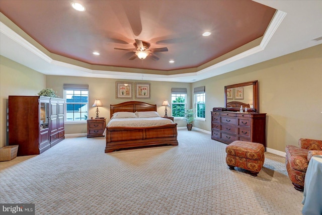 bedroom with a tray ceiling, carpet floors, baseboards, multiple windows, and crown molding
