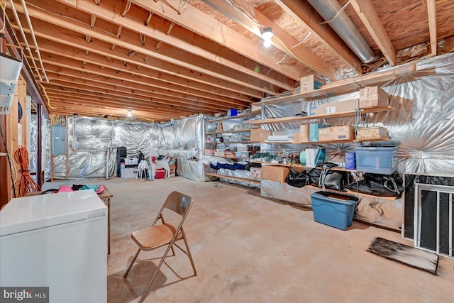 unfinished basement with fridge and electric panel