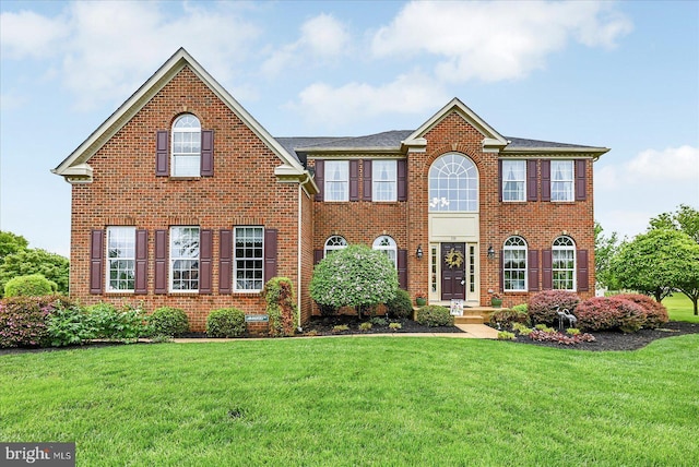 colonial-style house featuring a front lawn and brick siding