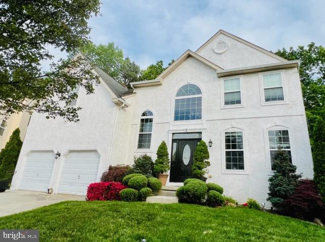 view of front of house featuring a garage, driveway, stucco siding, and a front lawn