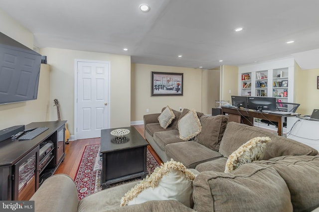 living room with dark wood finished floors, recessed lighting, built in shelves, baseboards, and an office area