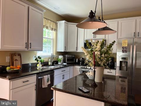 kitchen featuring stainless steel fridge, black dishwasher, a sink, a kitchen island, and dark stone counters