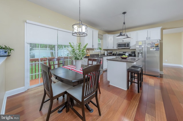 dining space featuring light wood-style flooring, plenty of natural light, and baseboards