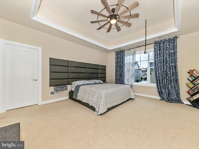 carpeted bedroom featuring a tray ceiling, baseboards, and a ceiling fan