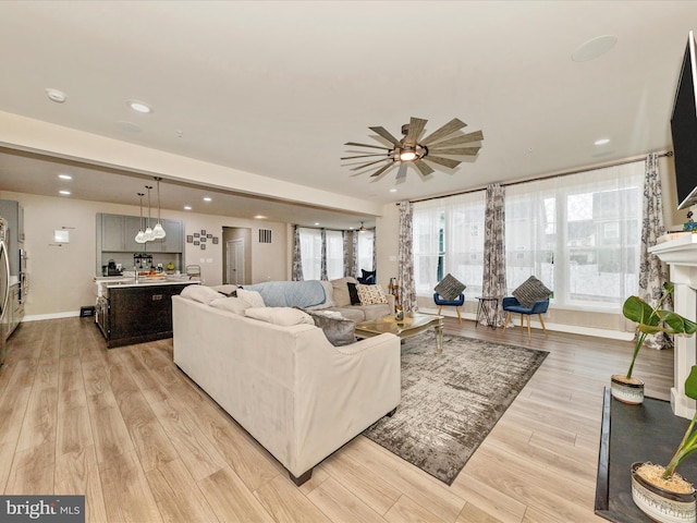 living area with light wood-style floors, ceiling fan, recessed lighting, and baseboards