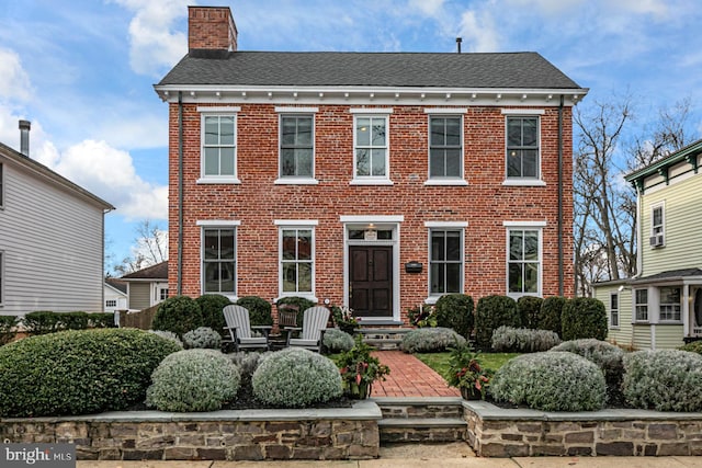 view of front of house with a chimney and brick siding