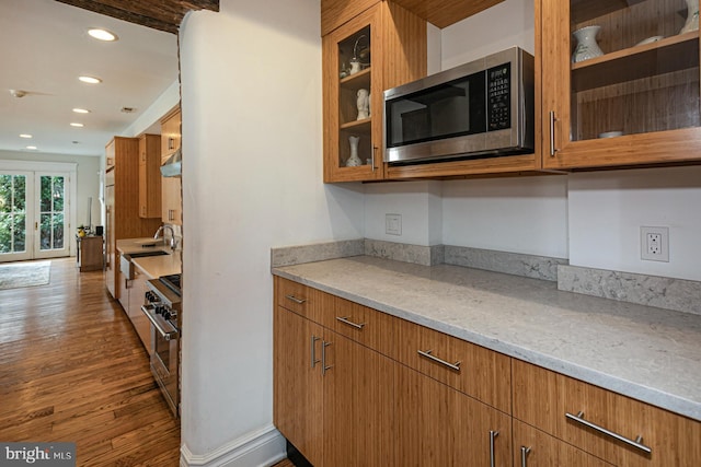 kitchen with stainless steel appliances, dark wood-style flooring, recessed lighting, glass insert cabinets, and brown cabinetry