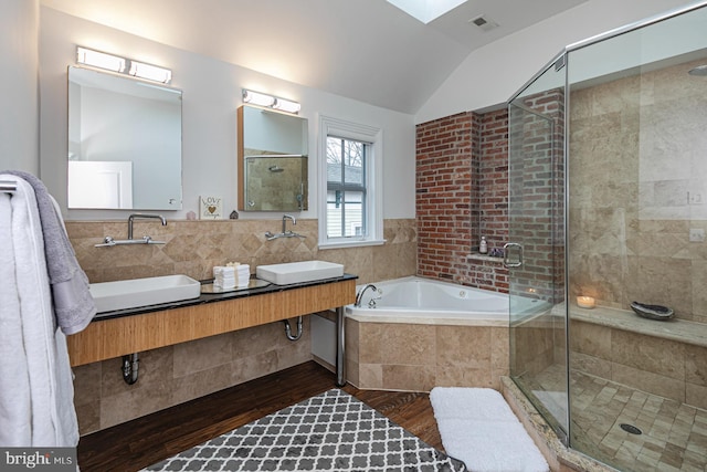 full bathroom featuring lofted ceiling, a stall shower, a bath, wood finished floors, and double vanity