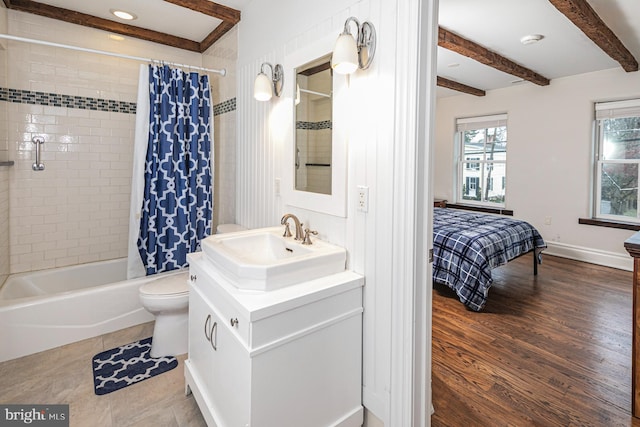ensuite bathroom featuring shower / tub combo, vanity, beamed ceiling, toilet, and baseboards