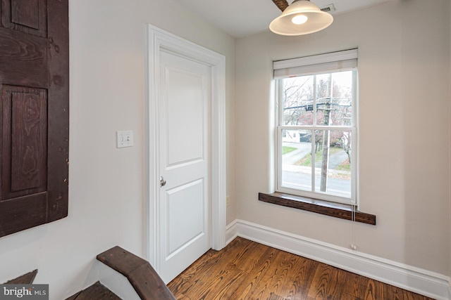 corridor with plenty of natural light, wood finished floors, and baseboards