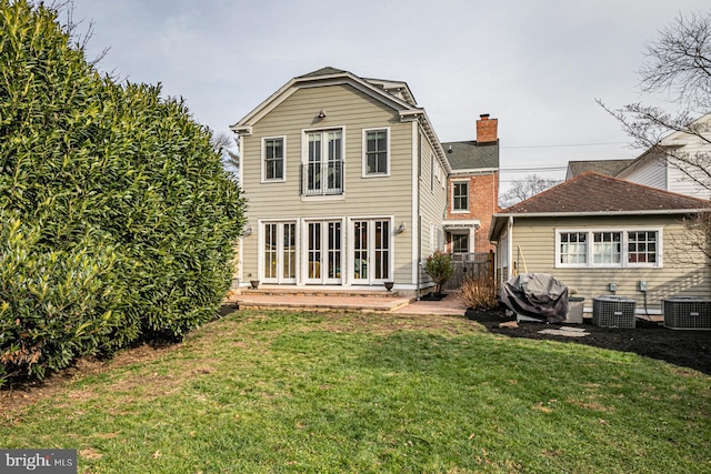 rear view of house with a lawn, central AC, and a chimney