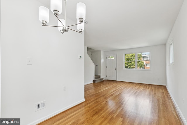 5817 Jamestown Rd, Hyattsville, MD 20782 - unfurnished living room with a chandelier, light wood-style flooring, stairway, and baseboards