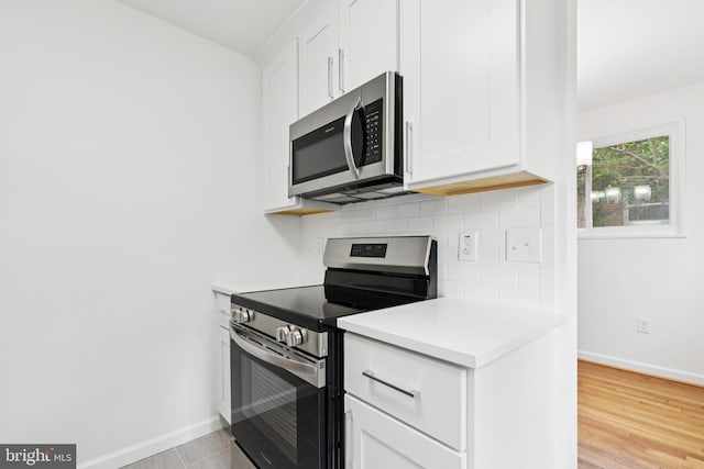 5817 Jamestown Rd, Hyattsville, MD 20782 - kitchen with stainless steel appliances, backsplash, baseboards, light countertops, and white cabinetry